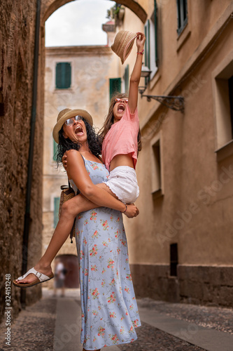 A laughing mother embraced her daughter in the narrow streets of Italy © studio GDB