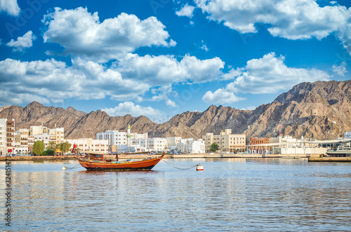 Old Sailboat anchored at Muttrah Corniche. The the old city and mountains in the background. From Muscat, Oman. photo