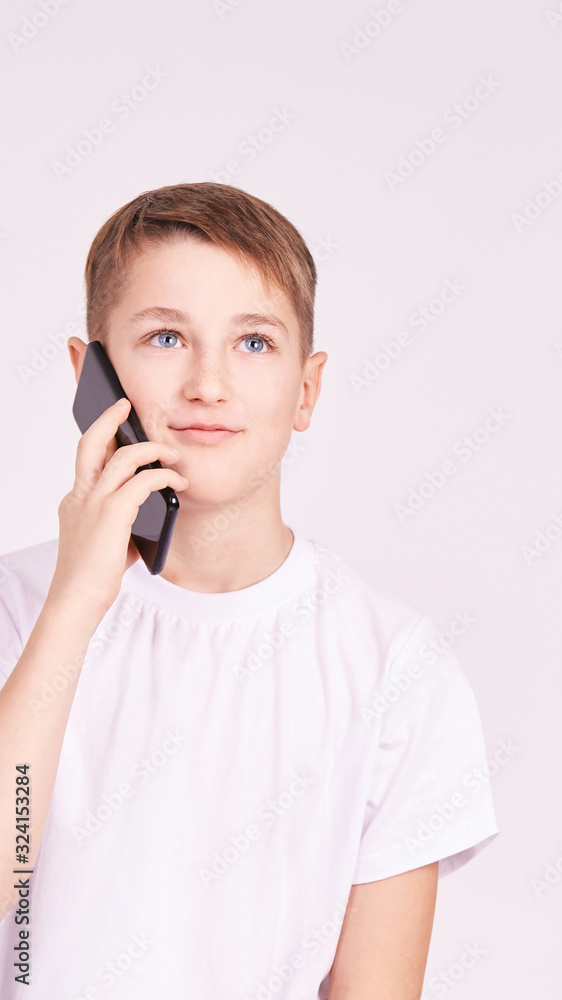 Young boy talking telephone. White shirt at grey background. Male people Young boy talking telephone. White shirt at grey background. Male people