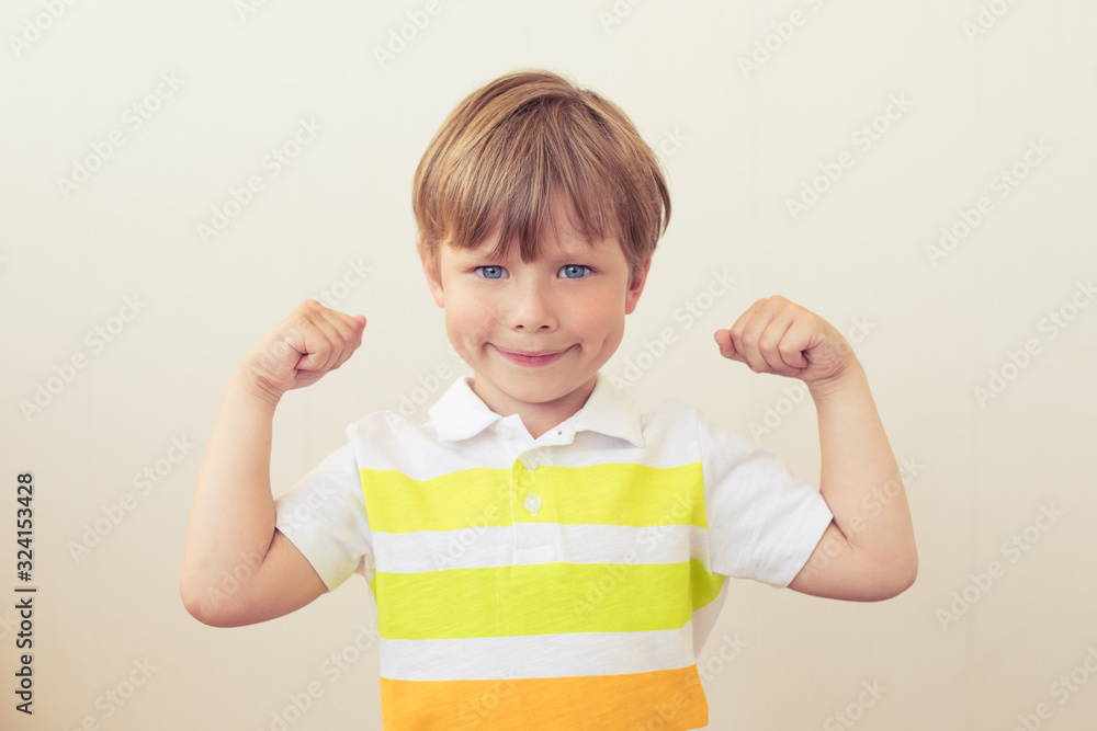 Portrait of a strong kid showing the muscles of his arms on white background Portrait of a strong kid showing the muscles of his arms on white background