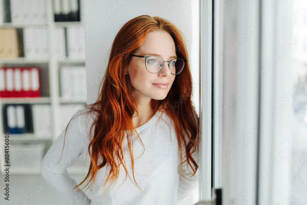 Quiet businesswoman looking through a glass door Quiet businesswoman looking through a glass door
