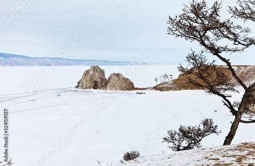 Baikal Lake in the winter. View of the famous Shamanka Rock and the snowy Small Sea Strait from the rocky coast of Olkhon Island. Winter landscape. Natural cold background