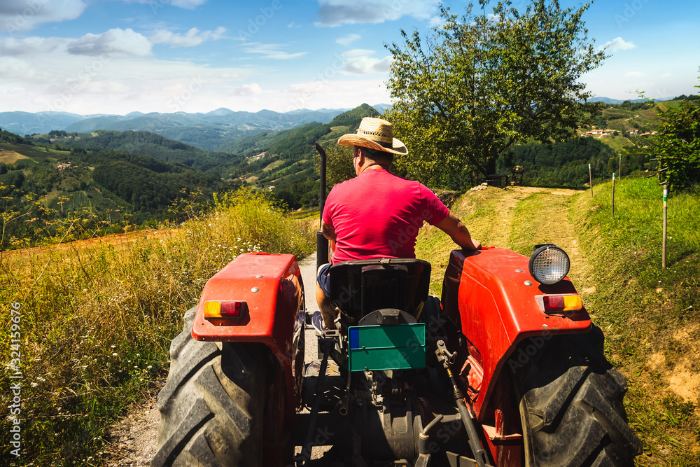 Obraz premium Man driving tractor in agricultural fields.