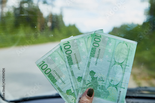 Euro banknotes in a woman hand inside of a car