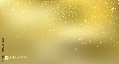 Sparkling golden glitter lights on gold blurred background.