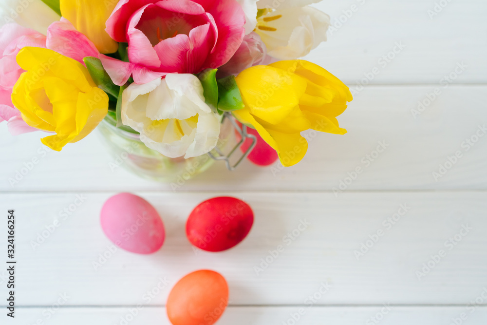 Obraz premium Fresh spring flowers with painted eggs for Easter celebration