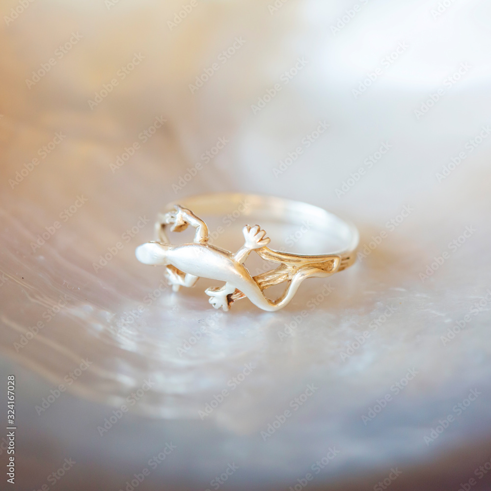 Sterling silver ring in shape of lizard on white shell background Sterling silver ring in shape of lizard on white shell background