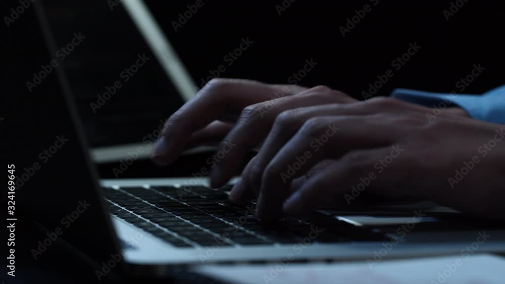 Close up hands of  businessman typing on laptop computer keyword at night while working overtime in office 