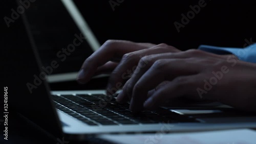 Close up hands of  businessman typing on laptop computer keyword at night while working overtime in office  photo