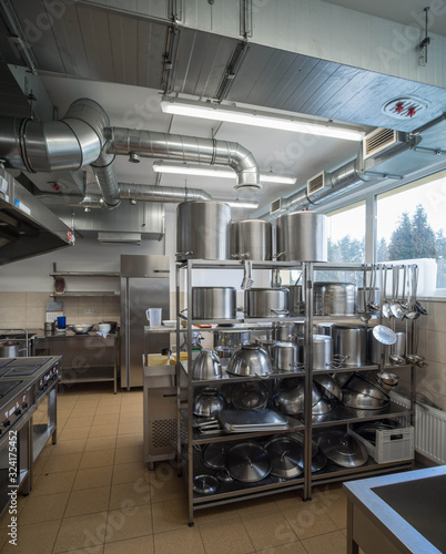 Interior of restaurant kitchen. Stainless steel pots. Metal piping ventilation system.