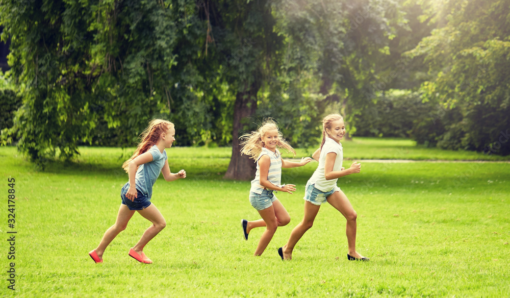 friendship, childhood, leisure and people concept - group of happy kids or friends playing catch-up game and running in summer park