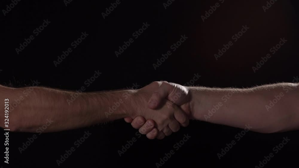 Caucasian males firmly shake hands on black background, close up isolated, 4K Caucasian males firmly shake hands on black background, close up isolated, 4K