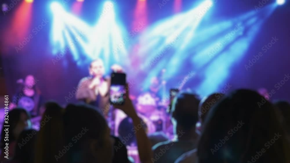 People with phones in their hands at a concert shoot everything that happens on stage. Blurred silhouettes of dancing crowd in an outdoor concert. People with phones in their hands at a concert shoot everything that happens on stage. Blurred silhouettes of dancing crowd in an outdoor concert.