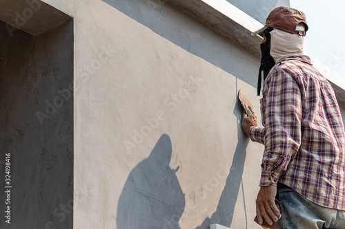 Worker scrubbing the cement walls with sandpaper and prepare the surface for painting.