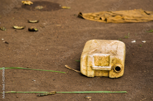 Water crisis in Uganda, an old yellow water container laying on the ground after being used to fetch contaminated drinking water from the next puddle