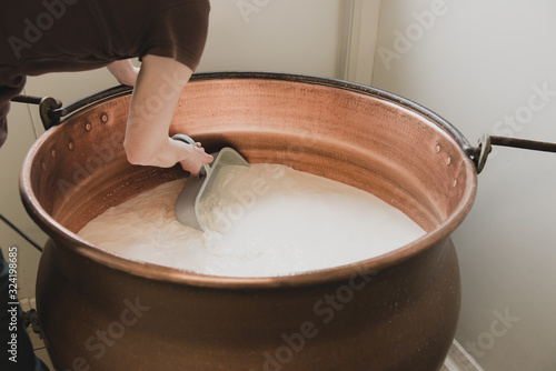 Agricultrice brasse du lait dans un chaudron photo