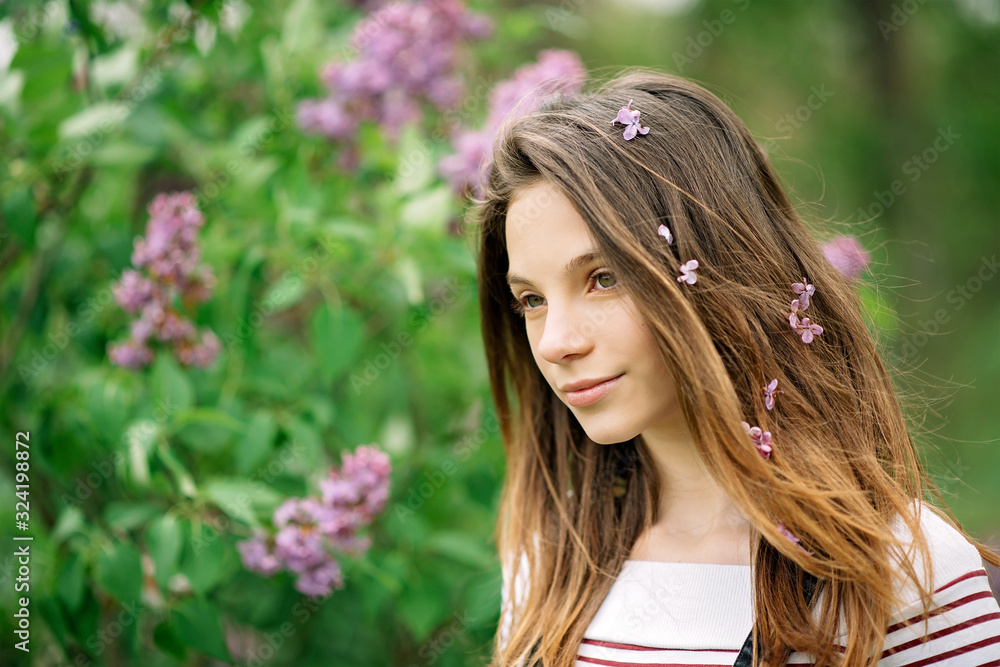 Beautiful young girl walking in the garden of a blooming lilac on a summer day. Copy space. Beautiful young girl walking in the garden of a blooming lilac on a summer day. Copy space.