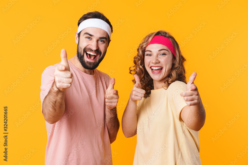 Portrait of athletic couple wearing headband smiling and pointing fingers