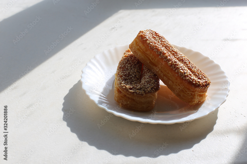 Piece of palmiers pastry, on the plate isolated on white background. With honey Piece of palmiers pastry, on the plate isolated on white background. With honey