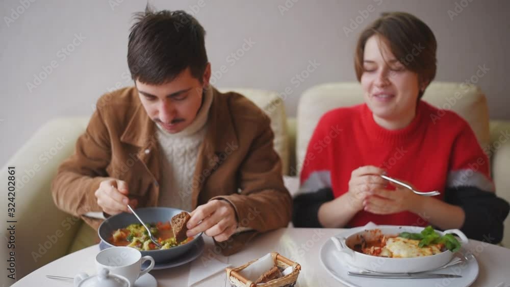 A guy and a girl have lunch in a restaurant. A young couple is eating in a cafe. A guy and a girl have lunch in a restaurant. A young couple is eating in a cafe.