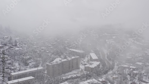 Flying in the clouds above snowy town Tkibuli, shoot in country of Georgia,  with drone 4K