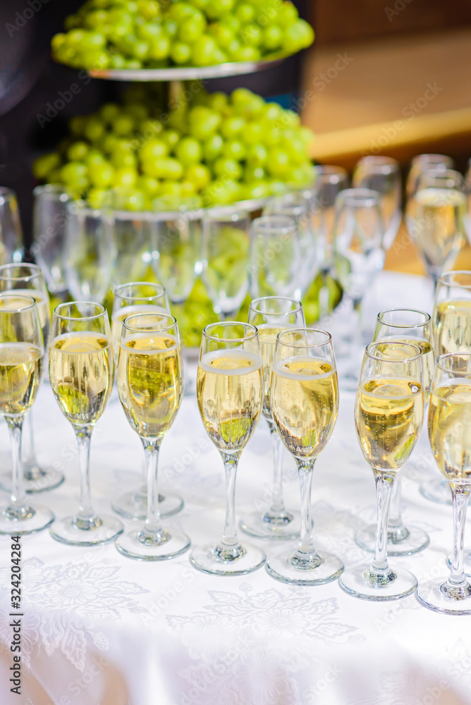 Glasses of champagne waiting for guests, grapes on the background Glasses of champagne waiting for guests, grapes on the background