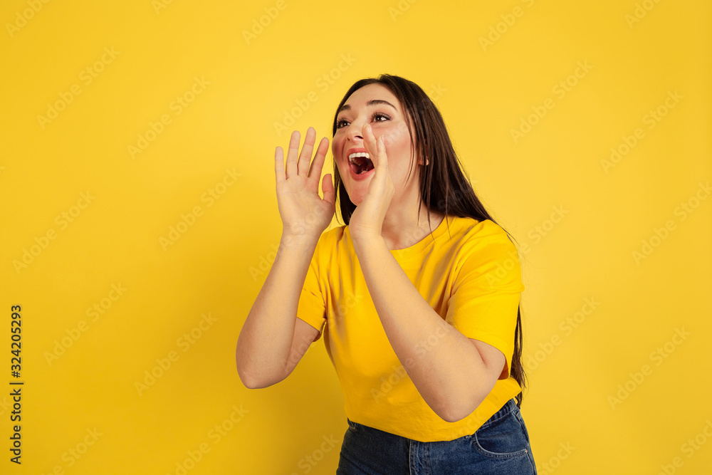 Calling for sales. Caucasian woman's portrait isolated on yellow studio background. Beautiful female brunette model in casual style. Concept of human emotions, facial expression, ad, copyspace. Calling for sales. Caucasian woman's portrait isolated on yellow studio background. Beautiful female brunette model in casual style. Concept of human emotions, facial expression, ad, copyspace.