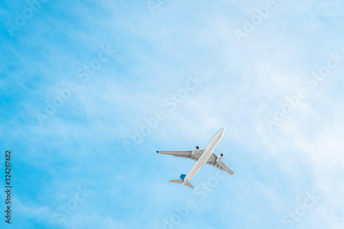 Large commercial passenger airplane flying under blue sky viewed from below