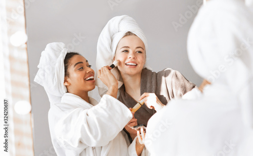 Afro girl helping her pretty girlfriend with make up