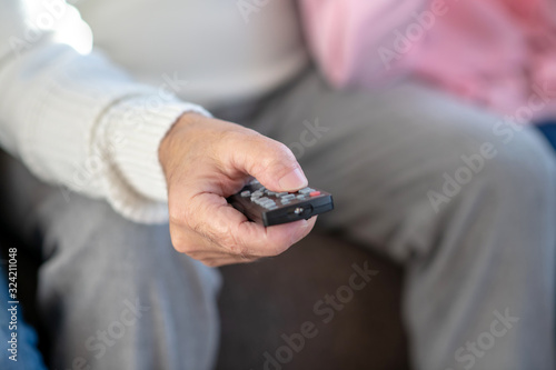Close up picture of a man sitting on the sofa with a remote control in his hand