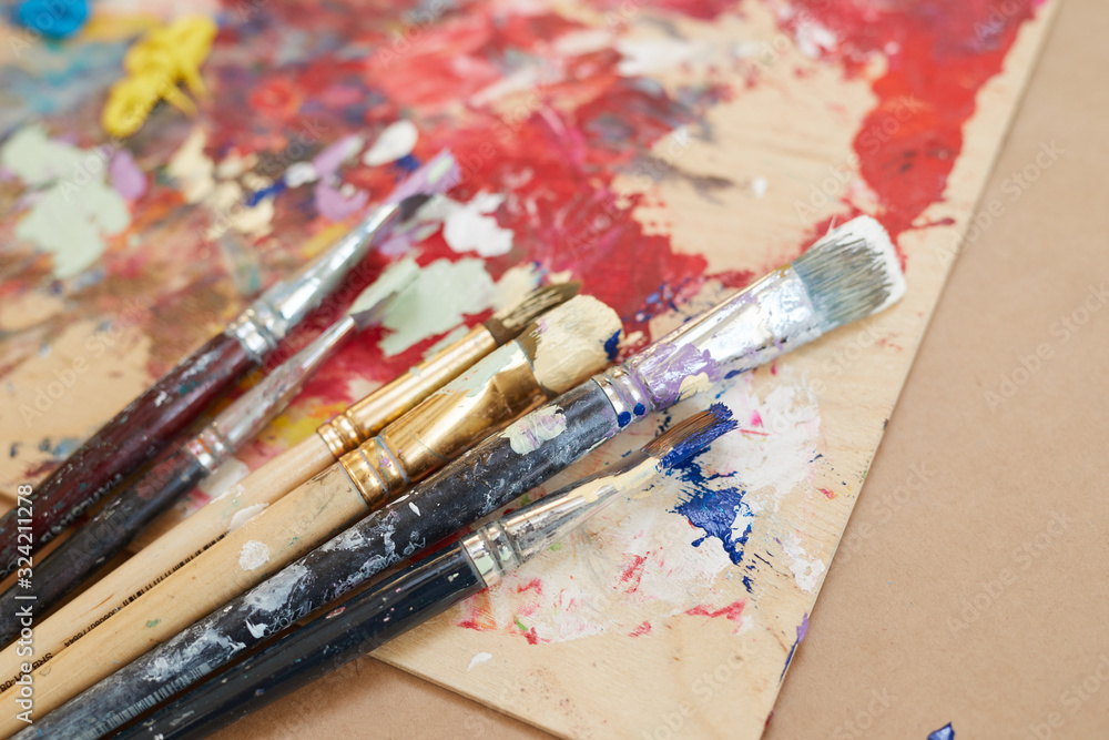 Close-up of different kinds of paintbrushes lying on the table with picture