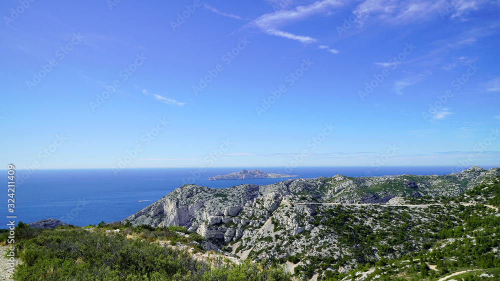 Fototapeta premium Blue sea and mountains nearby on a sunny day; beautiful coast under the blue sky