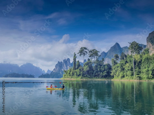 Lake view of tourists kayaking in the lake around with green forest, limestone mountains and cloudy sky background, Khao Sok National Park, Surat Thani, southern Thailand.