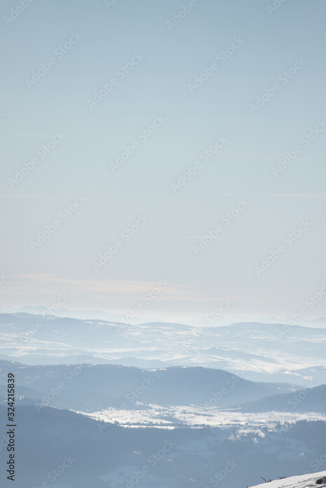 Beautiful view of the mountain range partially covered by fog and snow with clear blue sky. Beautiful view of the mountain range partially covered by fog and snow with clear blue sky.