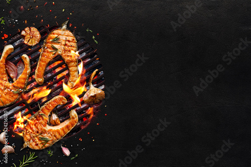Photography Grilled salmon fish  steaks and vegetables on a grill plate on black background with copy space