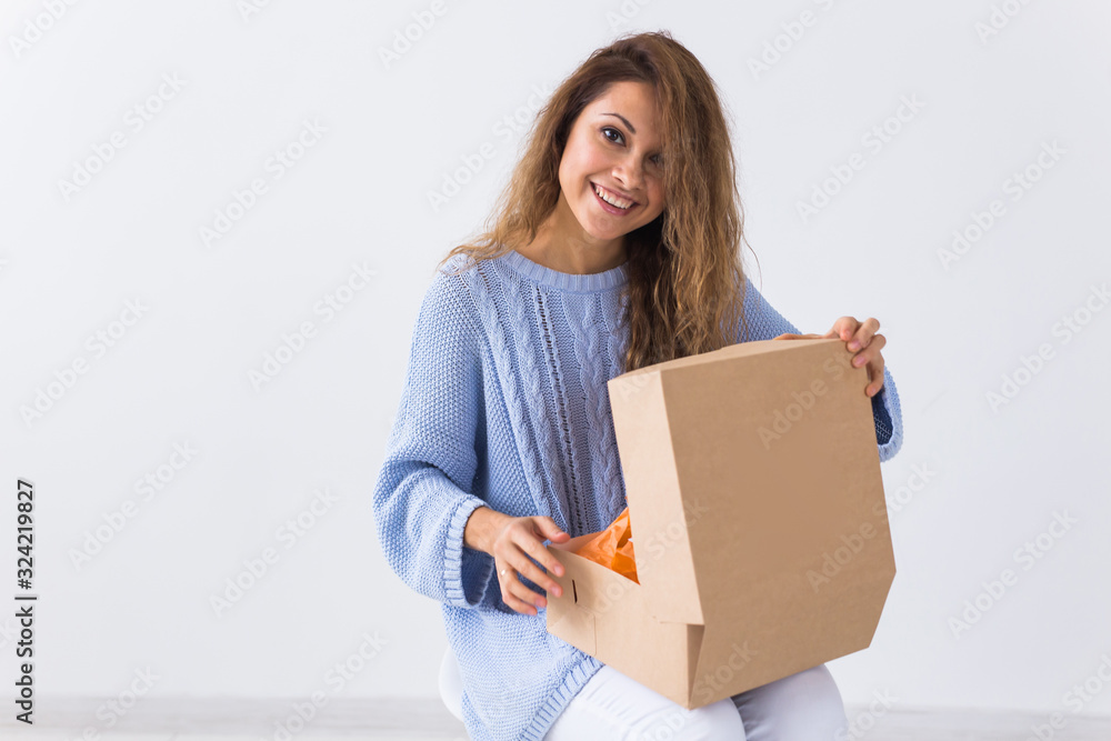 Online shopping, delivery and fashion concept - Woman sitting on sofa at home opening online clothing purchase Online shopping, delivery and fashion concept - Woman sitting on sofa at home opening online clothing purchase