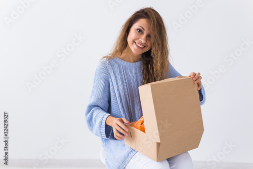 Online shopping, delivery and fashion concept - Woman sitting on sofa at home opening online clothing purchase © satura_
