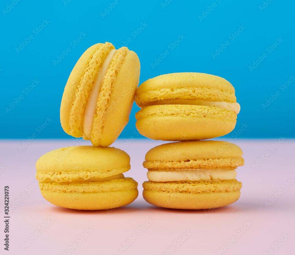 stack of baked round yellow lemon macarons on a blue-pink background stack of baked round yellow lemon macarons on a blue-pink background