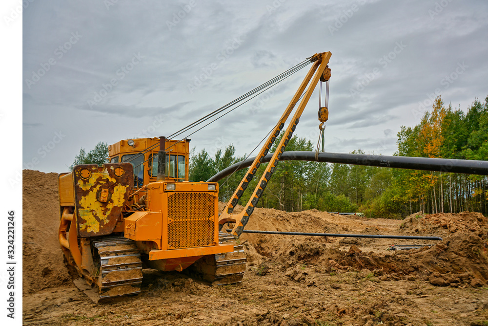 Pipelayer tractor lifts a pipe Pipelayer tractor lifts a pipe