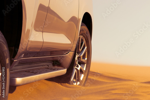 Close up of a golden car stuck in the sand in the Namib desert. Rear view with sunlight.