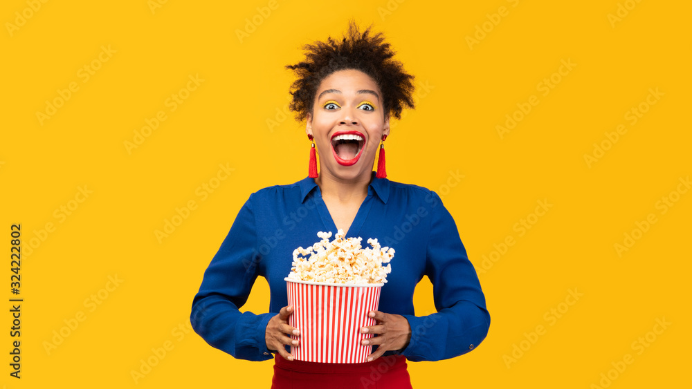 Millennial black girl with popcorn shaking popcorn