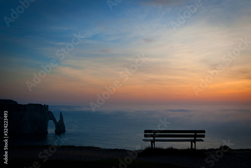 A bench, sea and rocks in the sunset sky. Etreta, Normandy, France