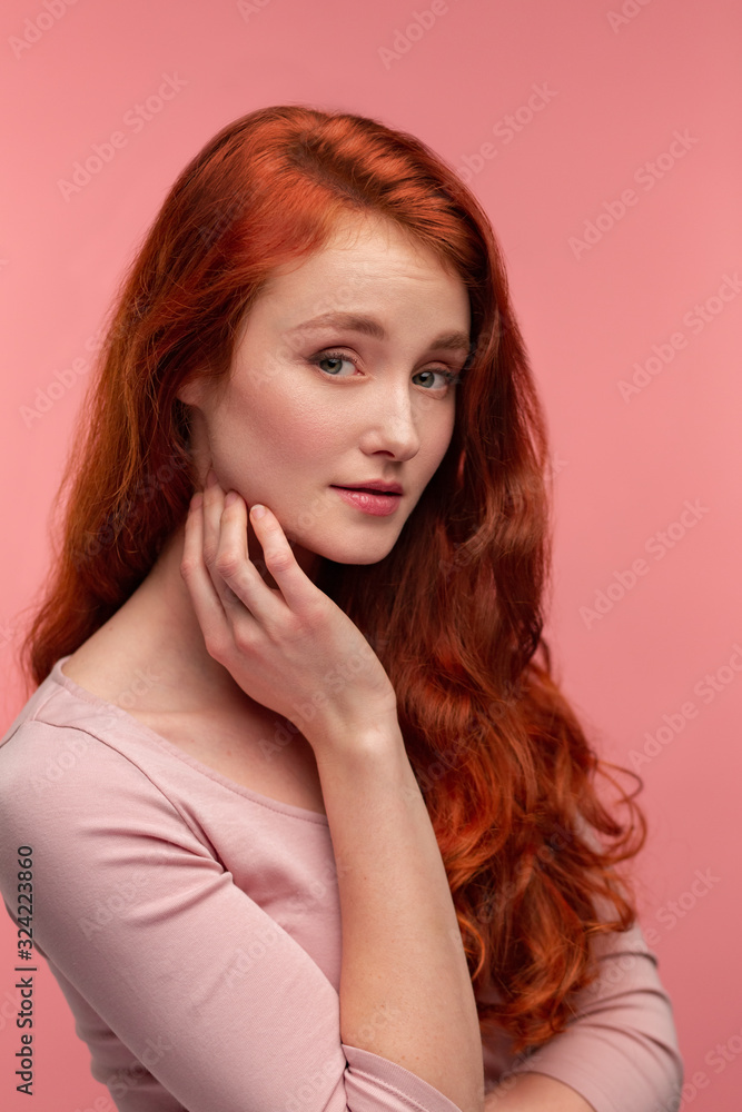 Portrait of smiling redhead girl. Perfect skin. Beautiful female model with long hair over pink background. Young cute woman with clear skin. Skincare and facial treatment concept. Portrait of smiling redhead girl. Perfect skin. Beautiful female model with long hair over pink background. Young cute woman with clear skin. Skincare and facial treatment concept.