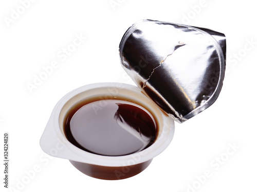 Plastic, open container with soy sauce on a white background