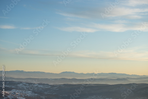 Beautiful view of the mountain range partially covered with snow just before sunset. Partly orange sunset sky © Zoran