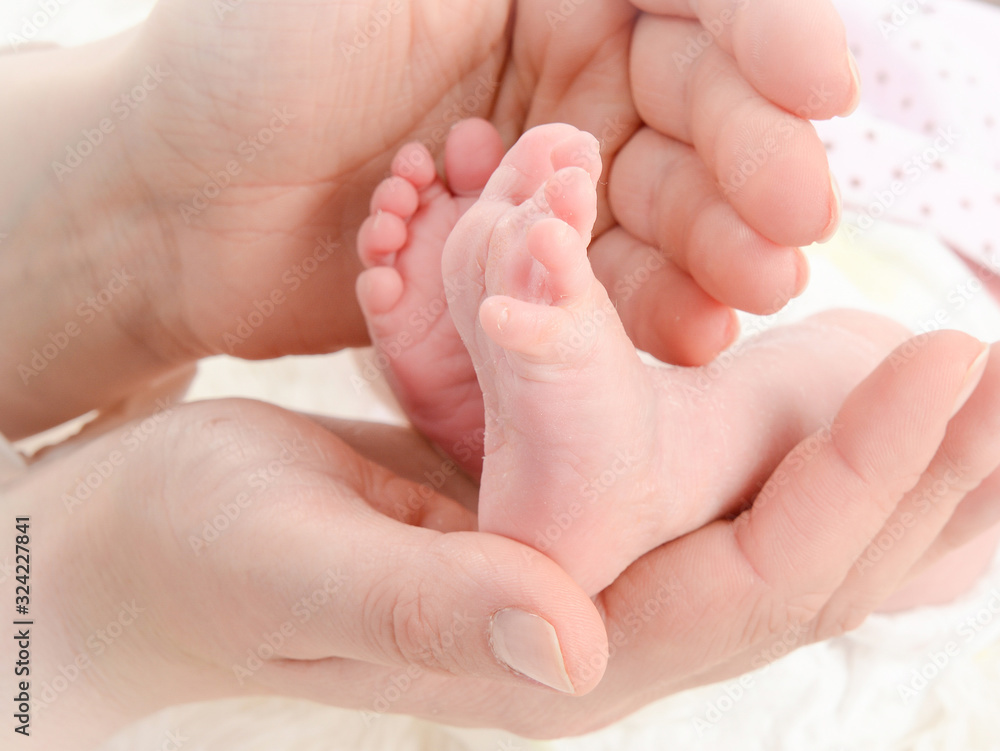 pies de recién nacido cogidos entre las manos de mamá pies de recién nacido cogidos entre las manos de mamá