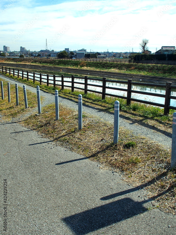 Fototapeta premium 早春の土手の小道のある放水路風景