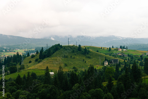 Ukrainian village in the Carpathian mountains in cloudy .day. Country side view of vertex in the middle of summer in nasty day. Rural landscape with forest, hills, authentic houses without people.