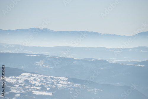 Beautiful view of the mountain range partially covered by fog and snow with clear blue sky. © Zoran