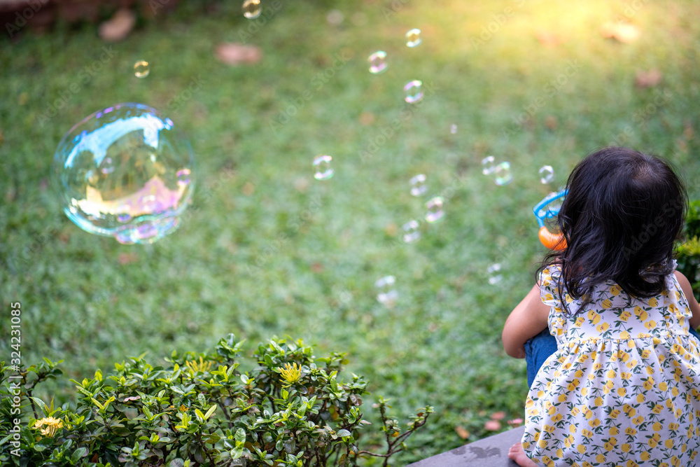 Cute little asian girl playing with soap bubbles in garden. Cute little asian girl playing with soap bubbles in garden.